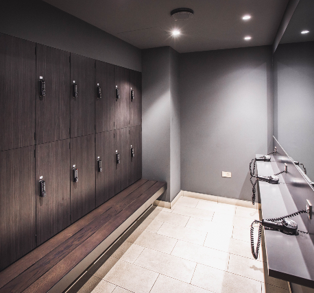 Gym changing room lockers with bench seating and hair drying station.