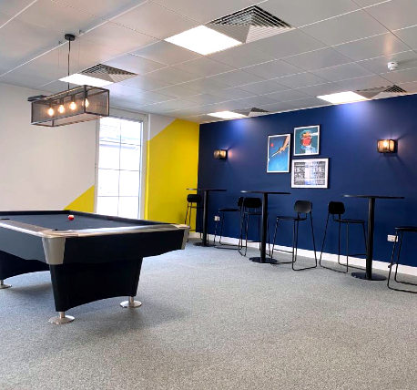 Office break area with tables, stools and pool table.