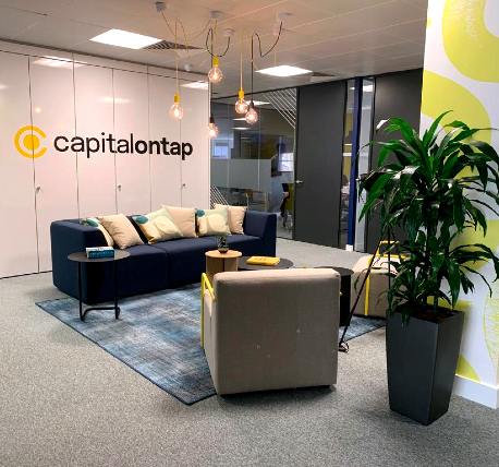 Office reception waiting area with blue sofa, storage and signage