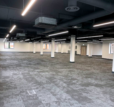 Open plan commercial office fully refurbished featuring grey carpet tiles, white walls, exposed ceiling