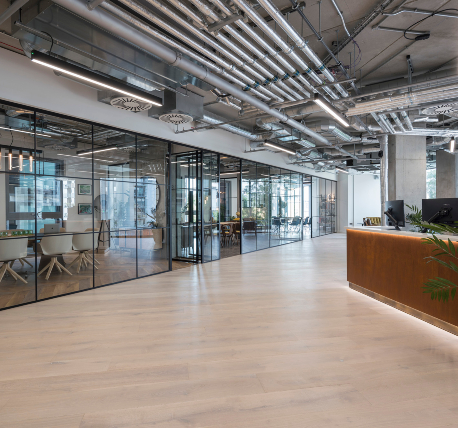 Glazed meeting room partitions, with black metal frames. Timber flooring and exposed ductwork on the ceilings.