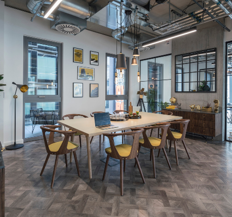 Meeting room with long table and timber chairs, wood effect flooring and exposed ductwork ceiling