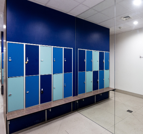 Changing room lockers in various shades of blue, with bench seat below