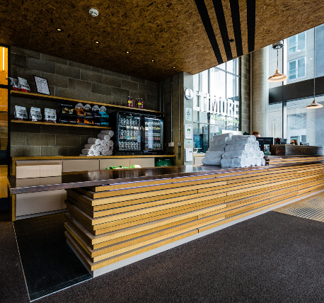 Bespoke reception desk for leisure club with bare timber slats stacked to create an overlapped effect