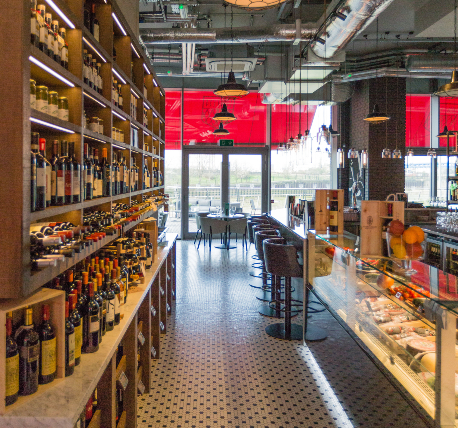 Restaurant counter with large wine rack display, patterned tile floor and hanging lights