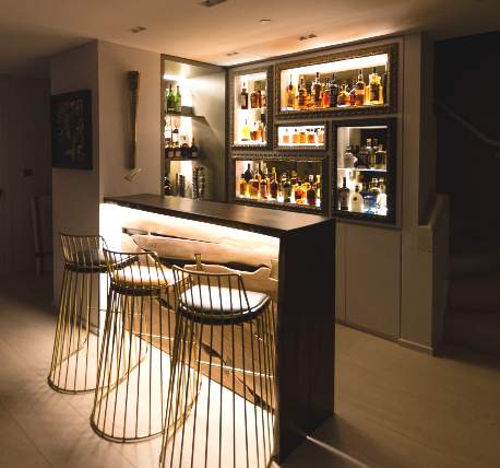 Private penthouse bar area with back lit shelving, and breakfast bar with stools