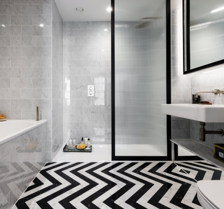 Modern bathroom with black framed frosted shower screen, black and white floor tiles and light grey wall tiles